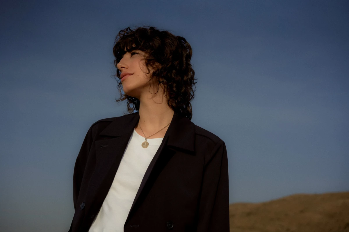 Young woman man in dark coat in open landscape at dusk for fashionable Mercedes campaign