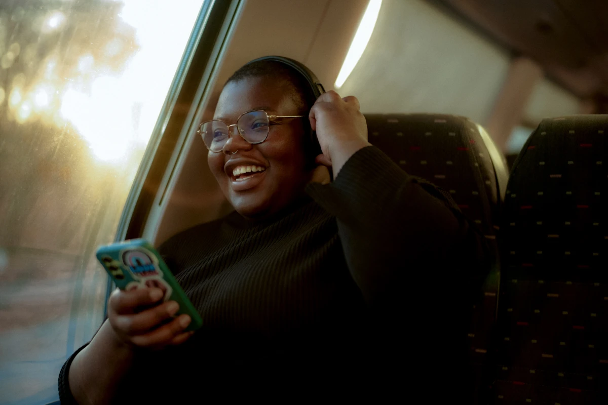 Woman smiling on train with smartphone in hand for SNCB rail travel campaign