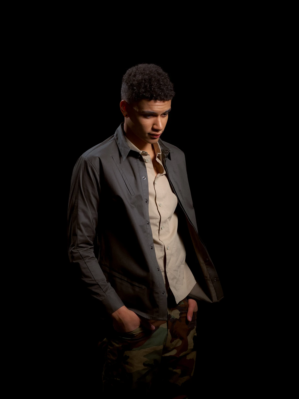 Young man in workwear jacket against black background for Carhart fashion portrait campaign