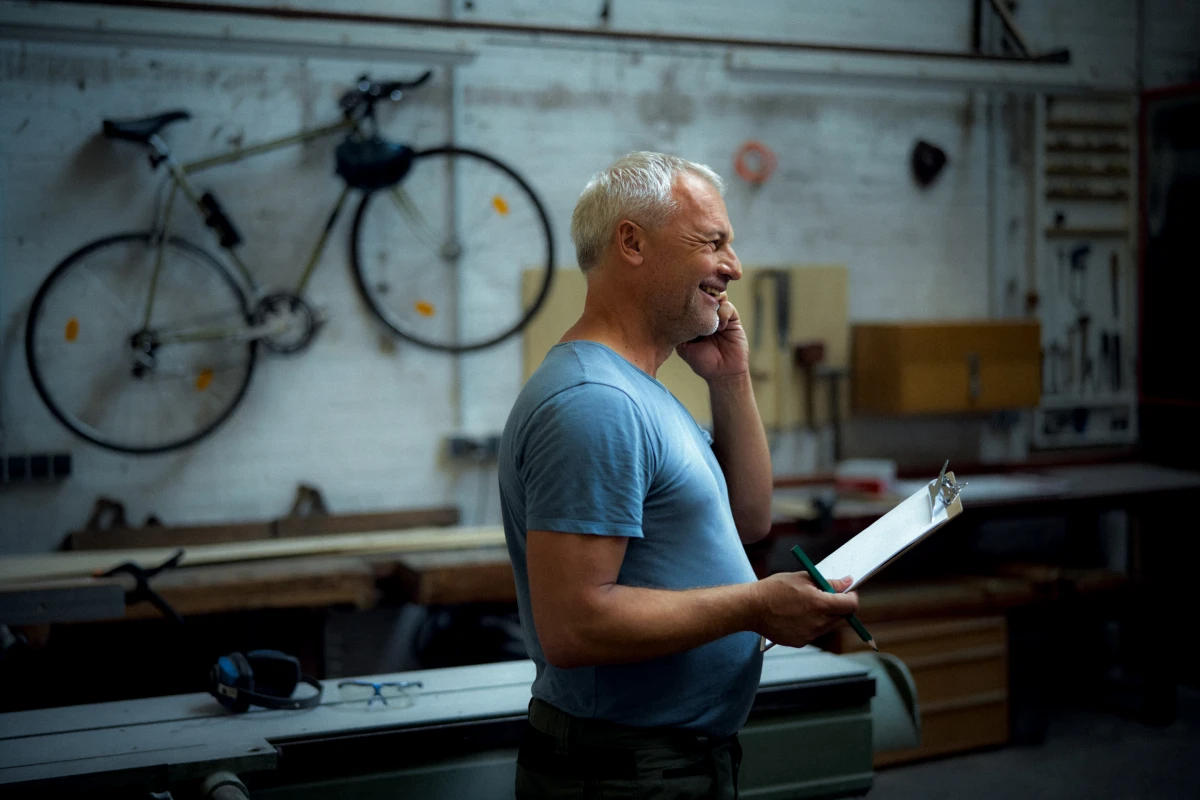 Older man in bicycle workshop speaking on phone for AOK health and everyday life campaign