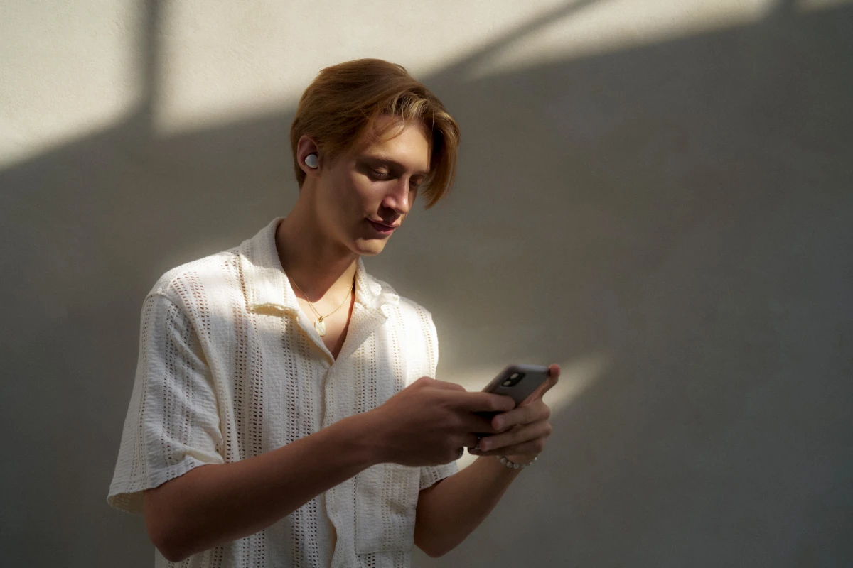 Young man checking smartphone in sunlit room for Samsung Galaxy mobile campaign