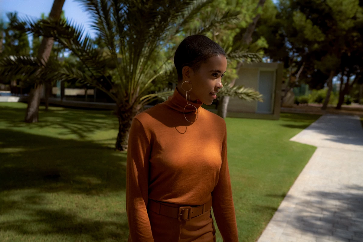 Woman in brown dress walking through palm-lined modern resort for Mercedes lifestyle campaign