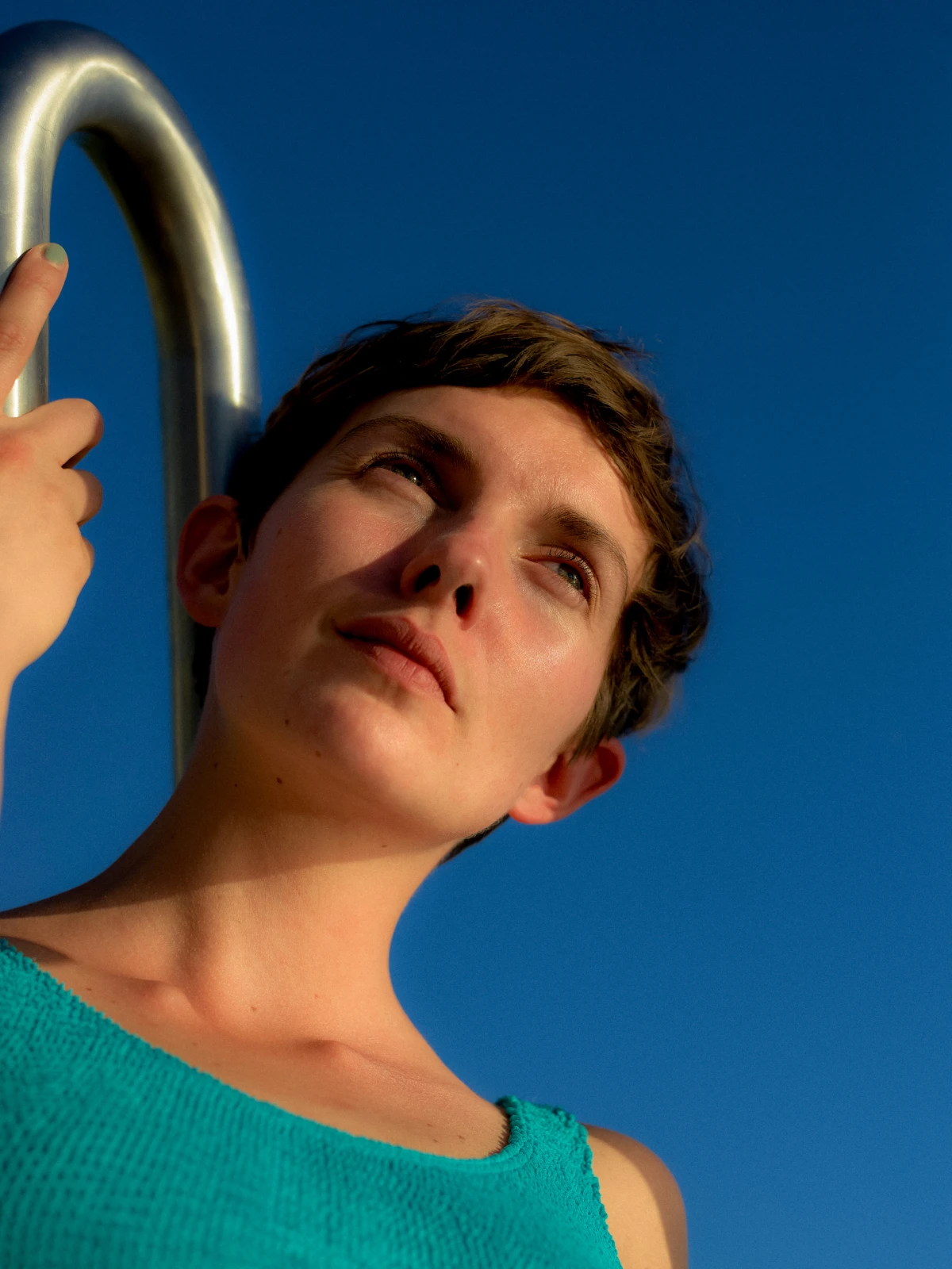 Young person holding metal ladder against blue sky for EON clean energy campaign