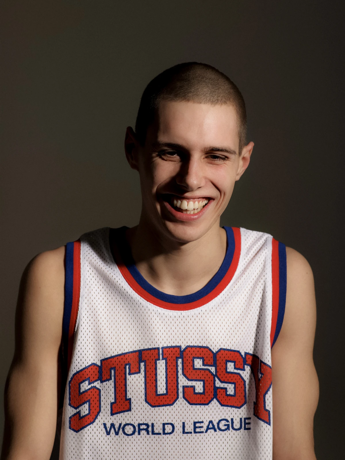 Smiling male model in Stussy basketball jersey against studio background for streetwear campaign