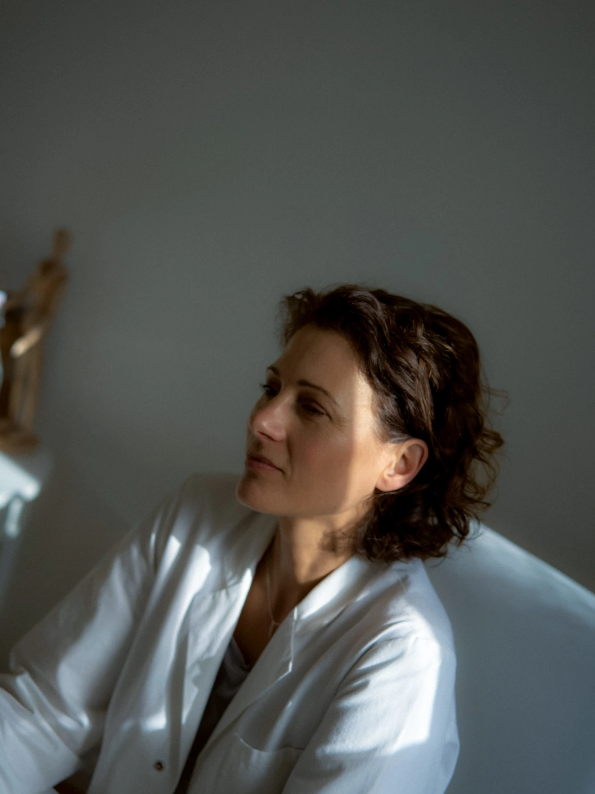 Female Doctor in white shirt sitting in soft window light for Deutsche Bank portrait lifestyle campaign