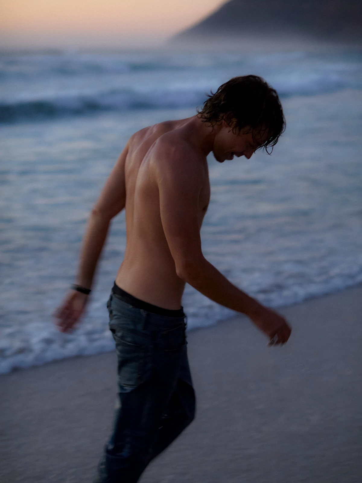 Young man walking shirtless along beach shoreline for Lee denim lifestyle campaign