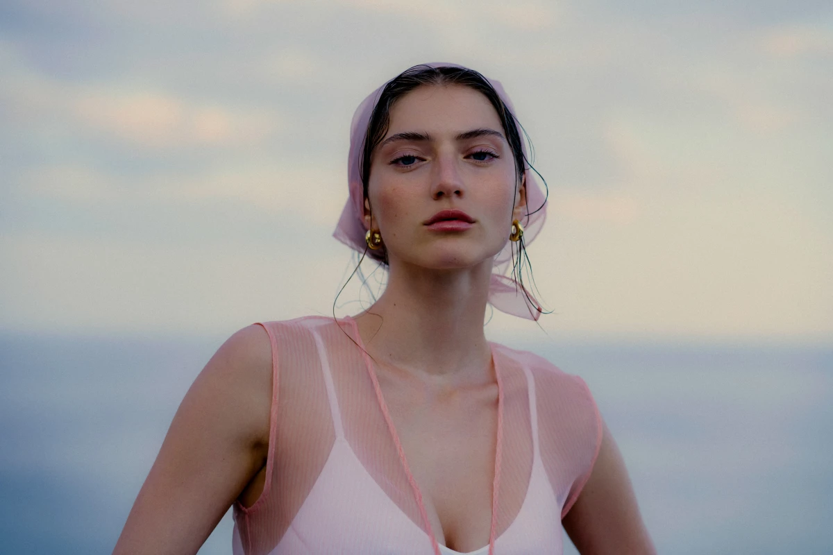 Young woman in pale pink dress by the sea for ELLE fashion editorial portrait geske advertorial