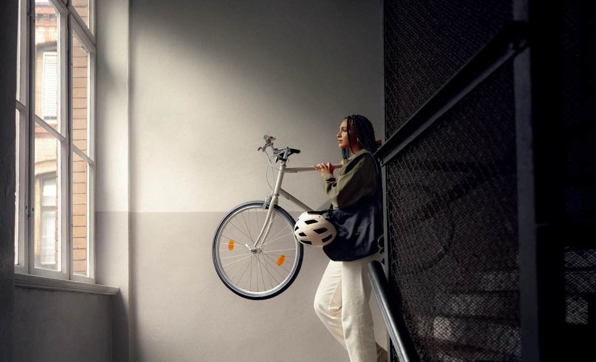 Person carrying bicycle up stairwell in natural light for AOK health insurance lifestyle campaign